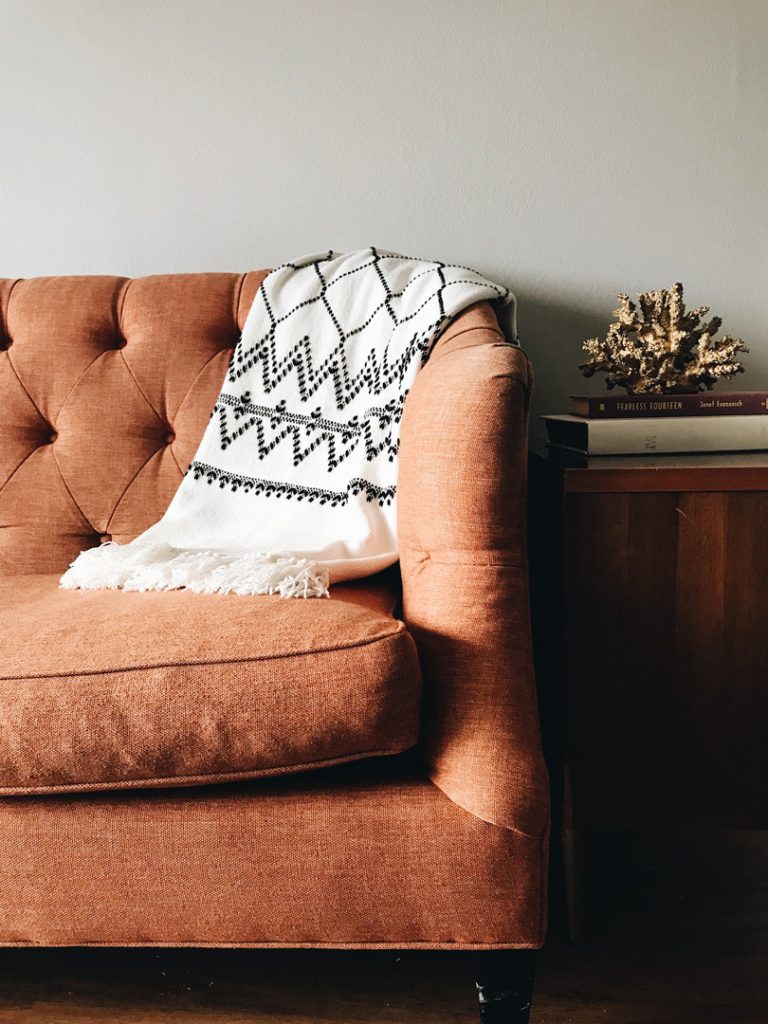 image of a sofa with a white nordic blanket thrown over | winter self care